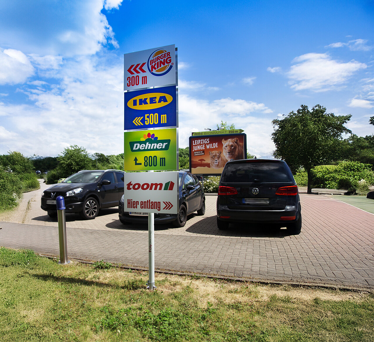 Wegweiser mit Markenwerbung auf einem Parkplatz