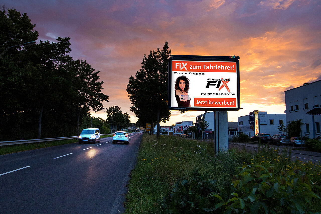 Großplakat mit 9 qm Werbefläche steht an befahrener Straße mit Fahrschul-Motiv