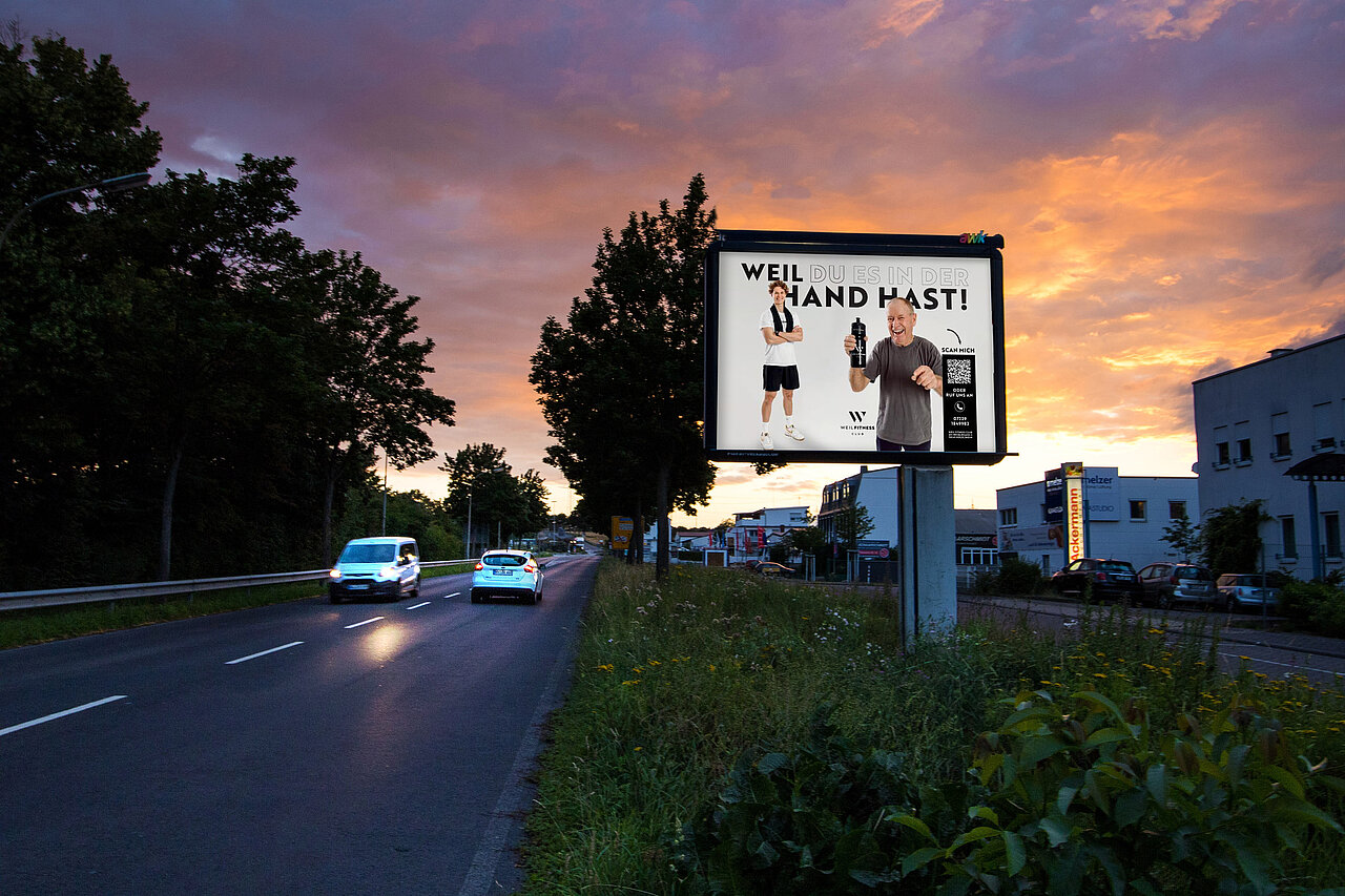 Großplakat mit 9 qm Werbefläche steht an befahrener Straße mit Fitness-Motiv