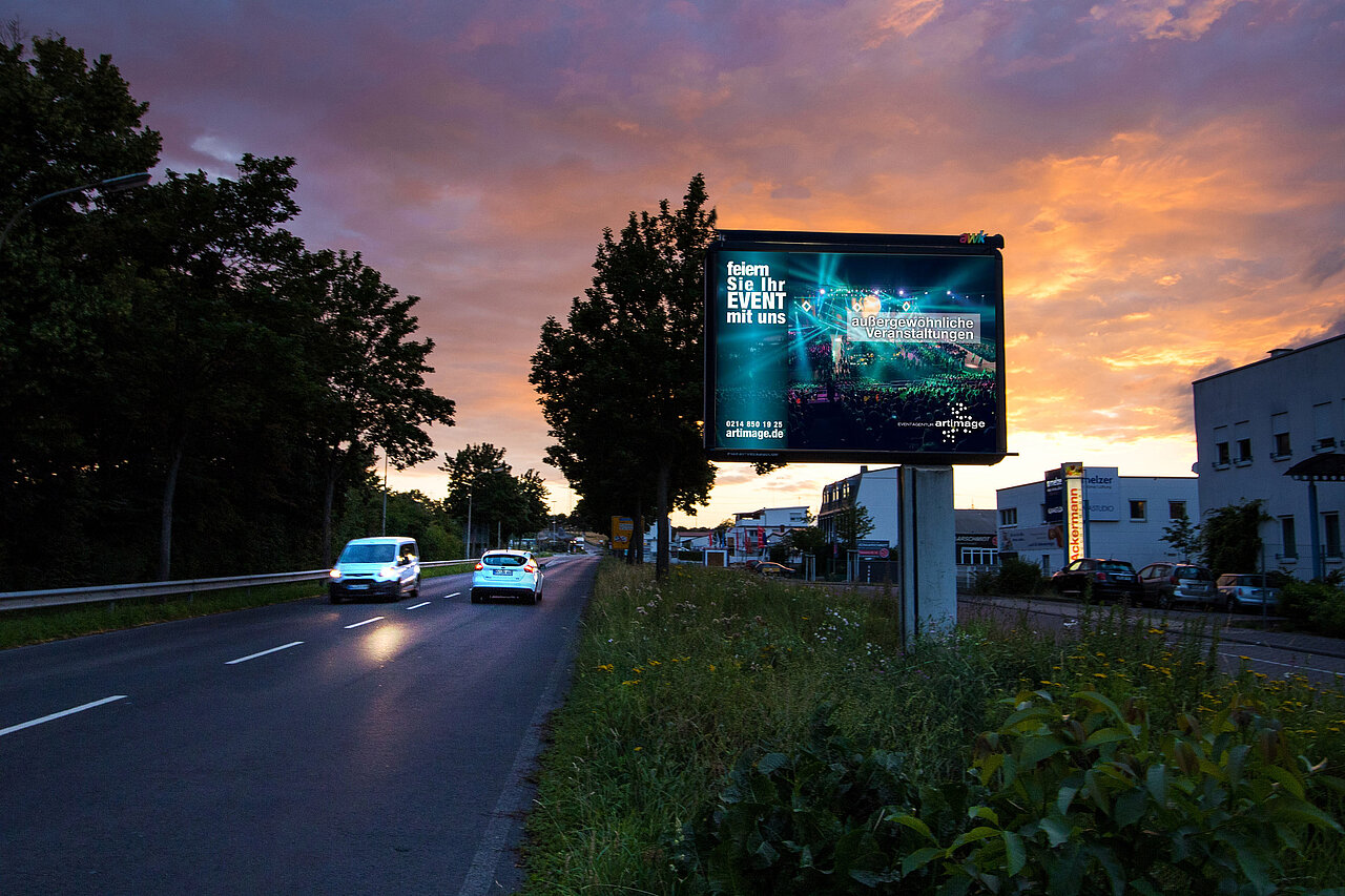 Großplakat mit 9 qm Werbefläche steht an befahrener Straße mit Veranstaltung-Motiv